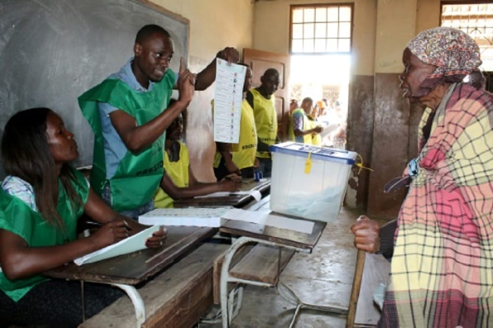 Un employé explique le processus de vote à une électrice à Maputo, le 10 octobre 2018